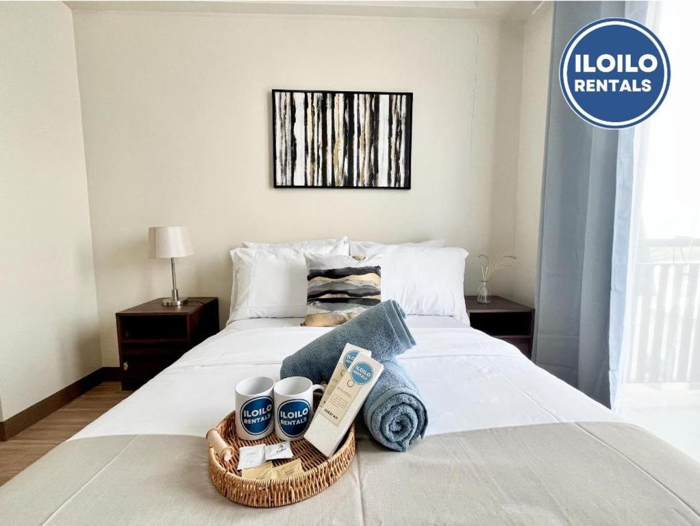 Luxury 1-Bedroom Stay at Saint Honore في Mandurriao: غرفة نوم مع سرير مع سلة من المناشف