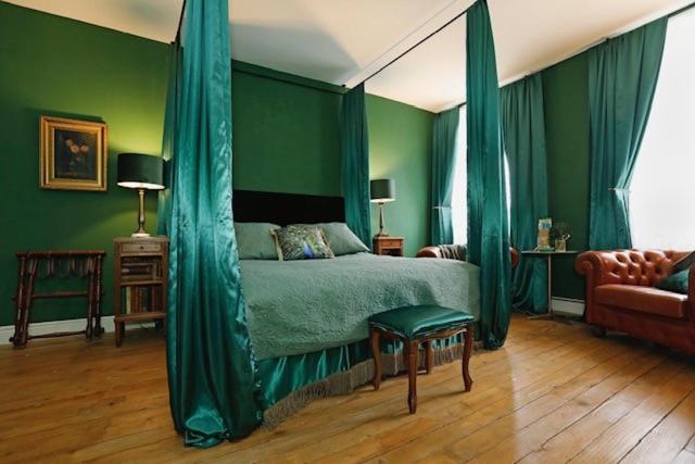 a bedroom with a bed with green walls and a couch at Villa La Poste 