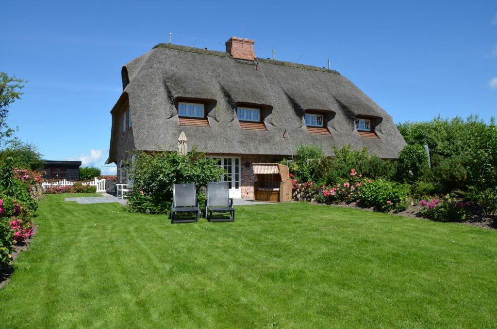 a thatched house with two chairs in the yard at LITZKOW 15005 in Morsum