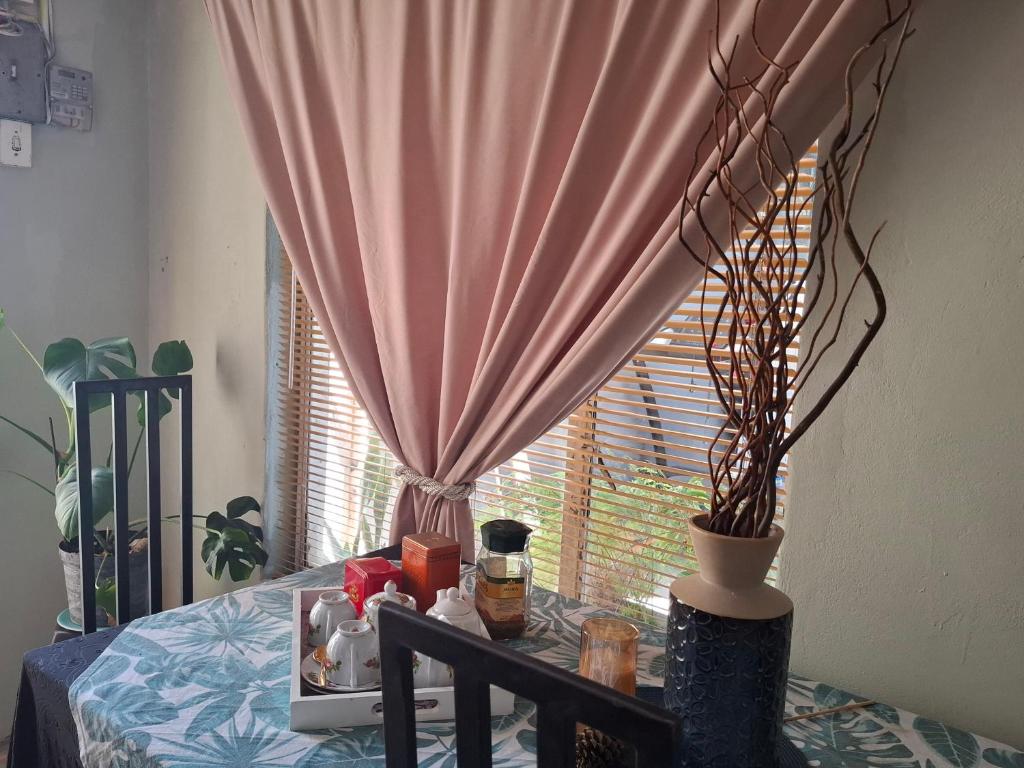 a table with a window with a pink curtain at The Albertyns in Belhar