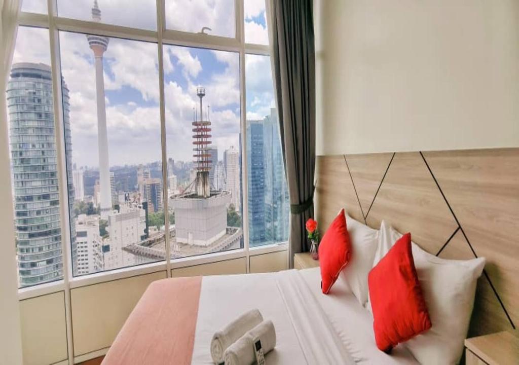 a bed with red pillows in a room with a large window at Sky Suites KLCC by TD Luxe Global in Kuala Lumpur