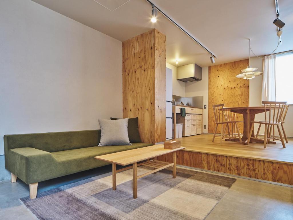 ein Wohnzimmer mit einer grünen Couch und einem Tisch in der Unterkunft TABiE in Izumo