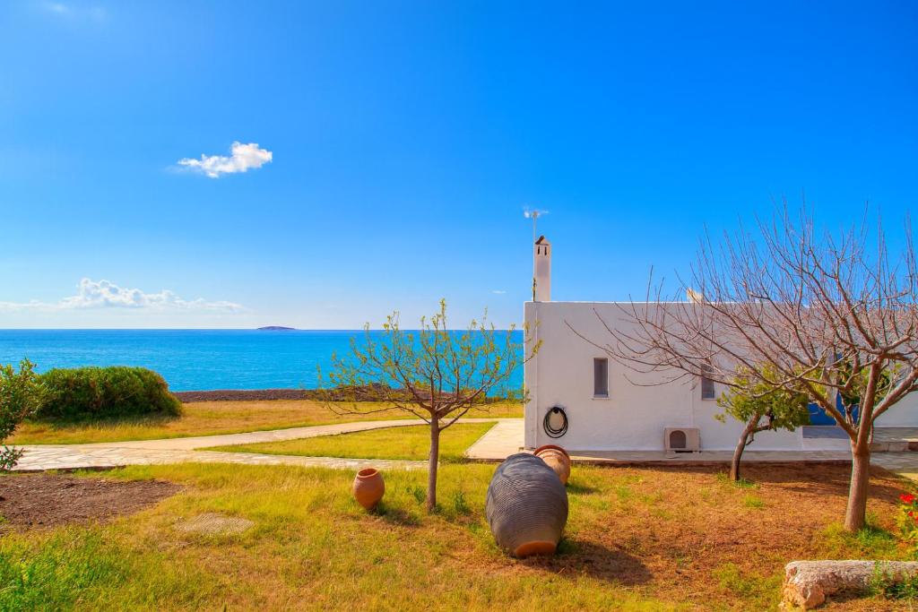 eine kleine weiße Kapelle mit dem Ozean im Hintergrund in der Unterkunft Aroura Homes 4BR Beachfront Villa in Spetses