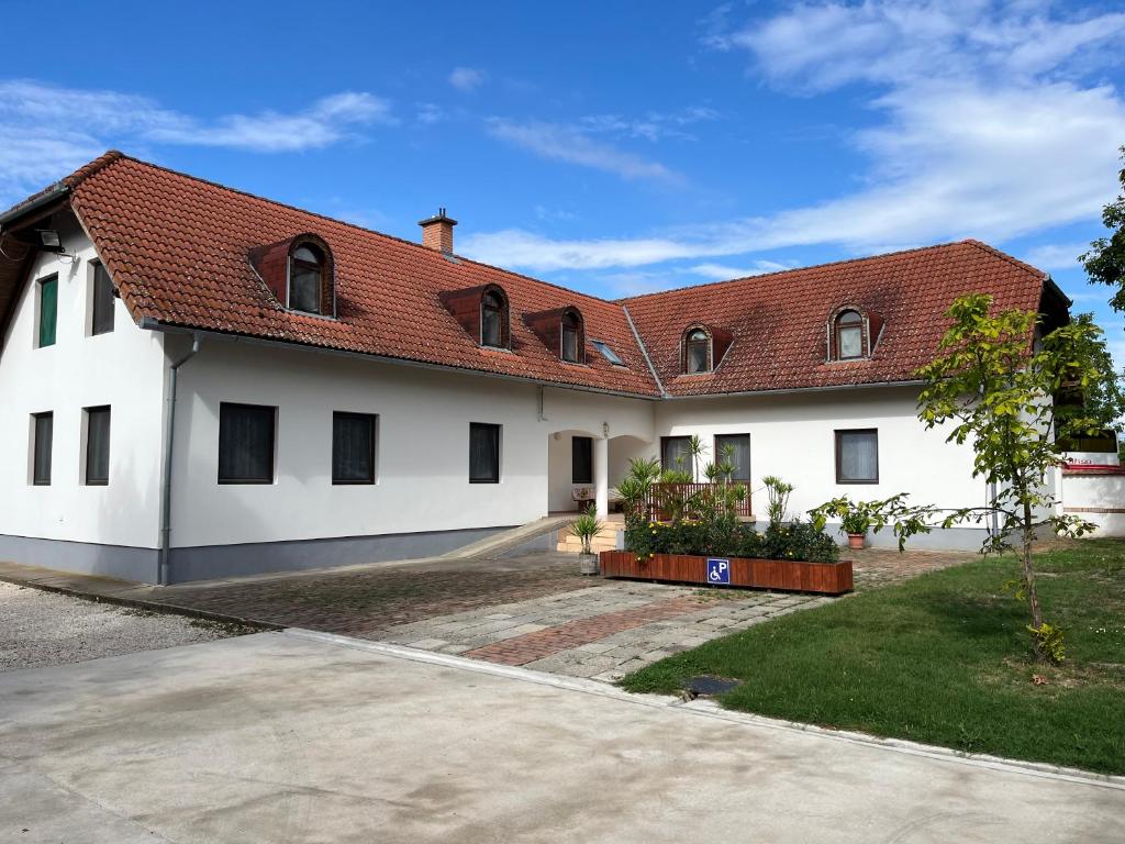 a white house with a red roof at Kormorán Vendégház in Matty