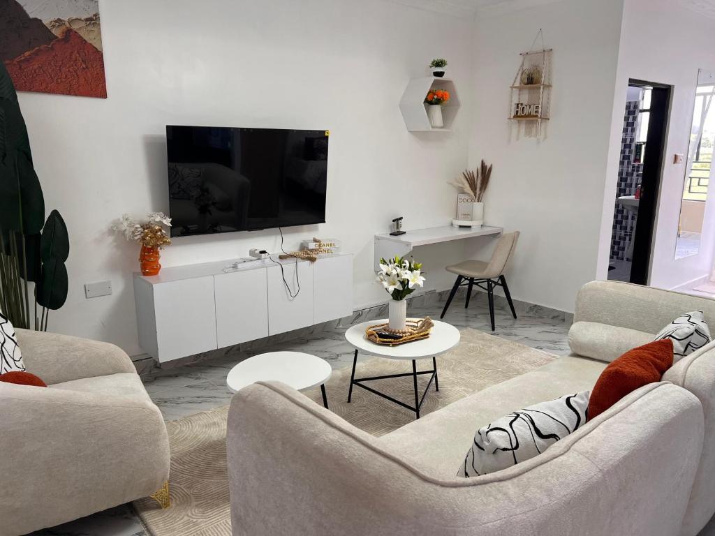 a living room with two couches and a flat screen tv at Studio in Nanyuki with Mount Kenya Views in Nanyuki