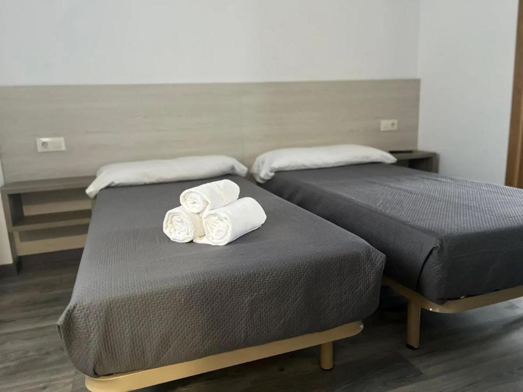 Dos camas con toallas en una habitación. en Albergue Miraiso, en Arzúa