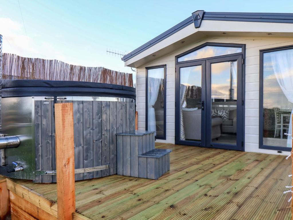 een huis met een terras met een hot tub bij Rosefinch Cabin in Staintondale