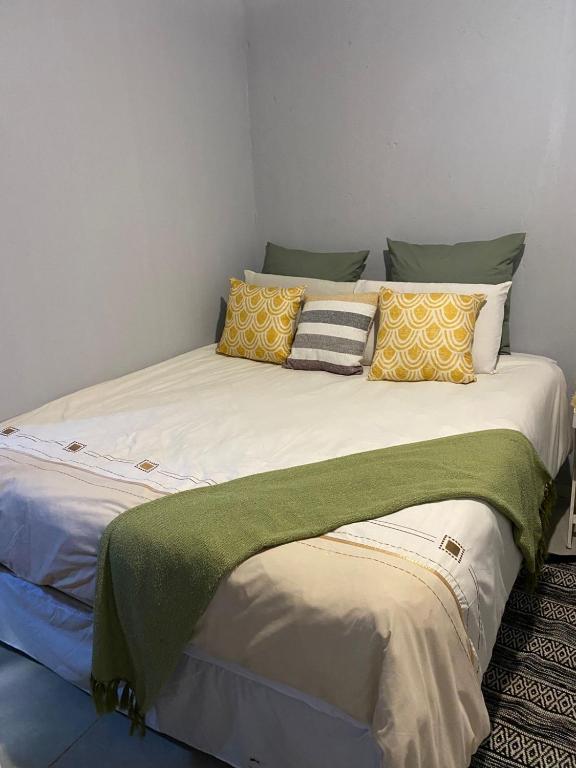 Thekiso Guest House في سنتوريون: سرير كبير عليه وسائد صفراء وخضراء