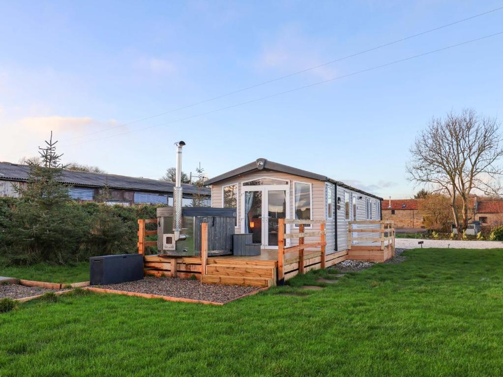 een klein huisje in een tuin met een groen gazon bij Swift Cabin in Staintondale