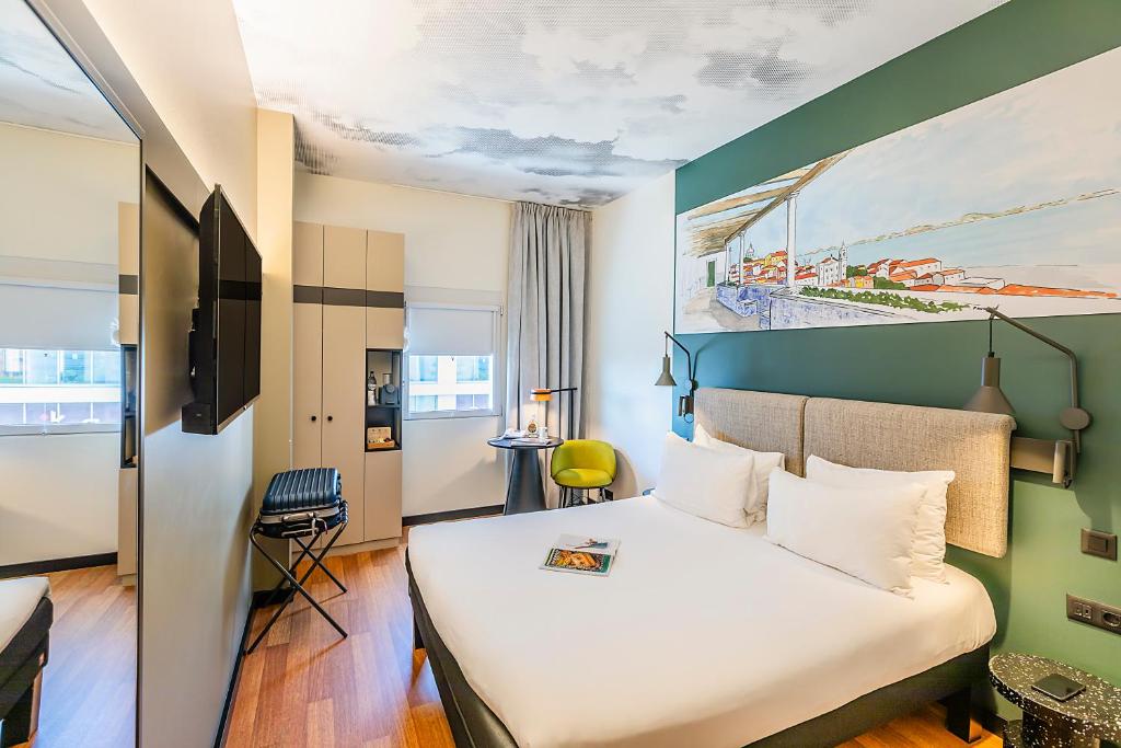 A modern double room with a wall-mounted television, wardrobe and colourful artwork.