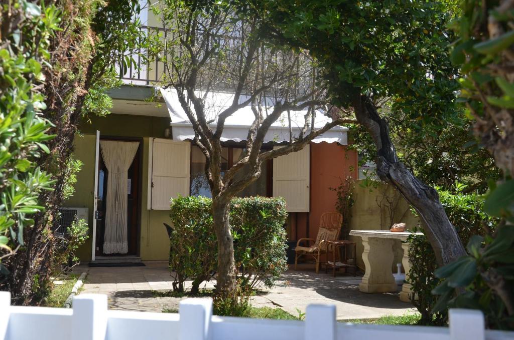 a garden with a house with a tree and a fence at FANTASTIC SARDINIA VILLETTE CON GIARDINO Fronte Mare Fertilia FAHO-GAV01-GAV02 in Fertilia