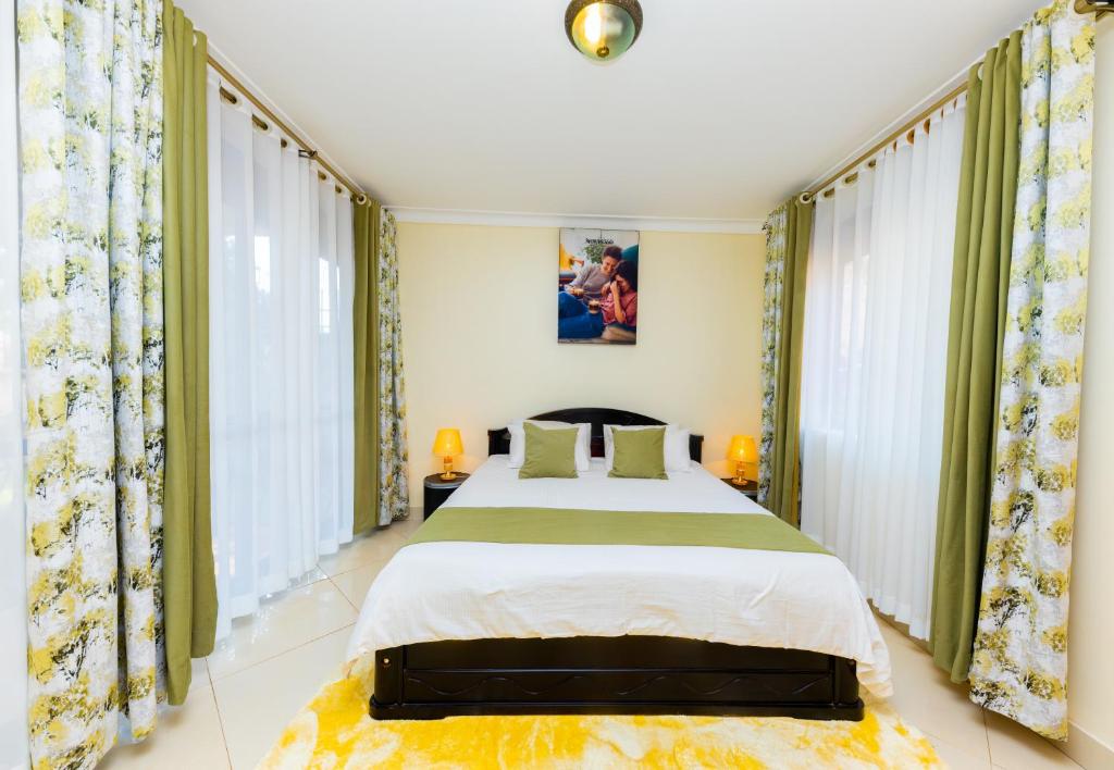 a bedroom with a large bed and windows at Luxury Homes and Apartments - Near Entebbe Airport in Kampala