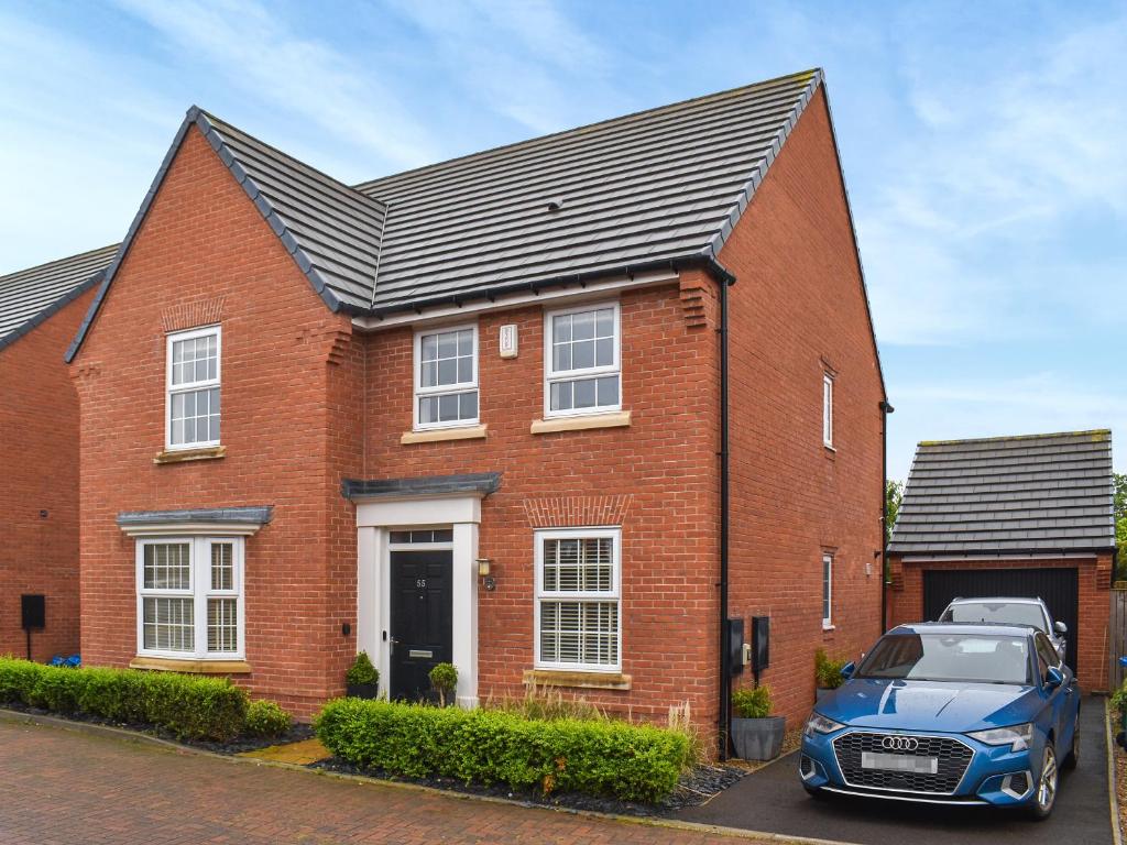 Song Bird Holiday Home في ويتبي: منزل من الطوب الأحمر مع سيارة متوقفة في الأمام