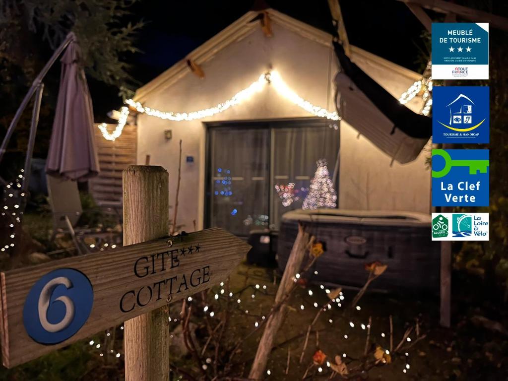 a sign in front of a white house with christmas lights at Cottage-Gite & Jacuzzi - Chez Flo & Marc in Chouzy-sur-Cisse