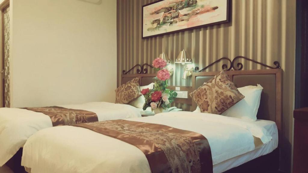 Bagan Serai的住宿－K Garden Hotel (BS)，两张床铺,位于酒店客房,墙上挂着鲜花
