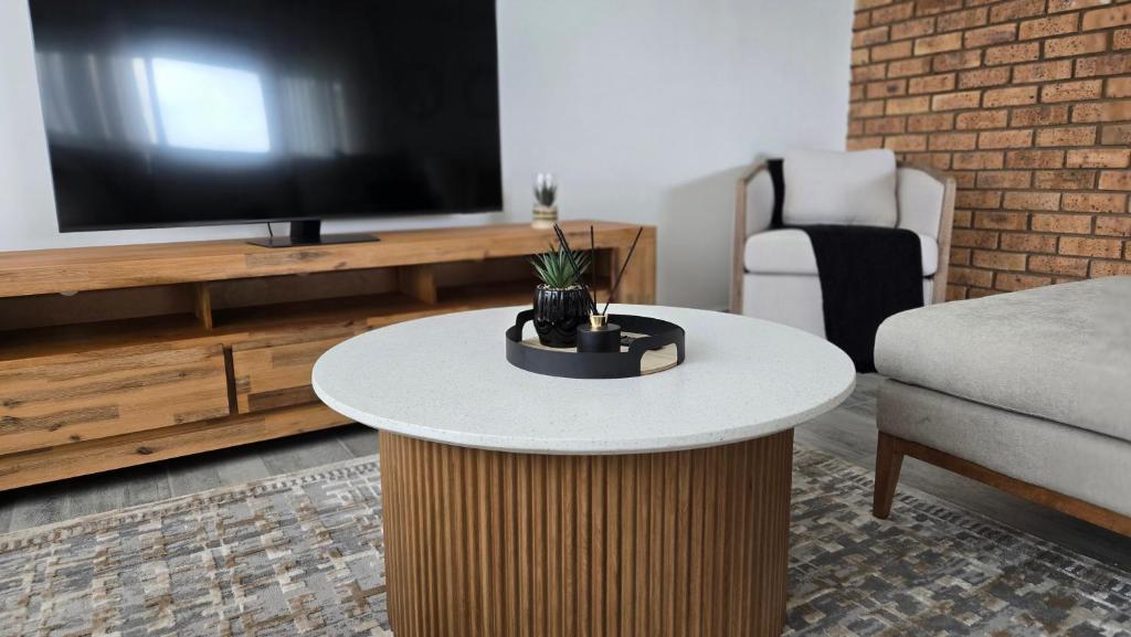 a living room with a table and a tv at Guernsey Home in Port Shepstone