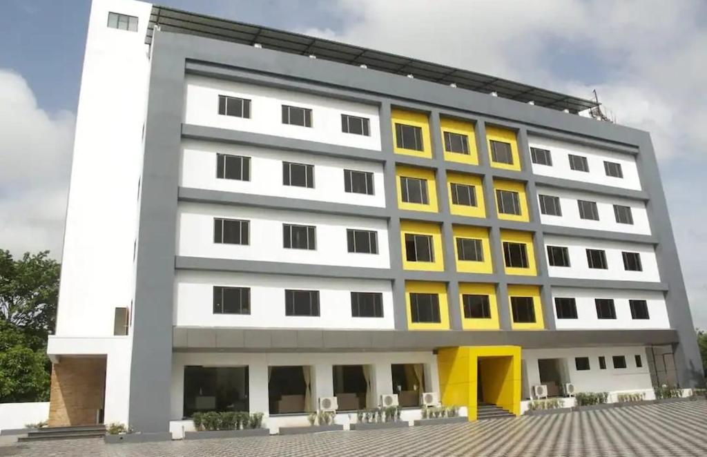 um grande edifício branco com janelas amarelas em Krushnai Resort em Kharakvasla