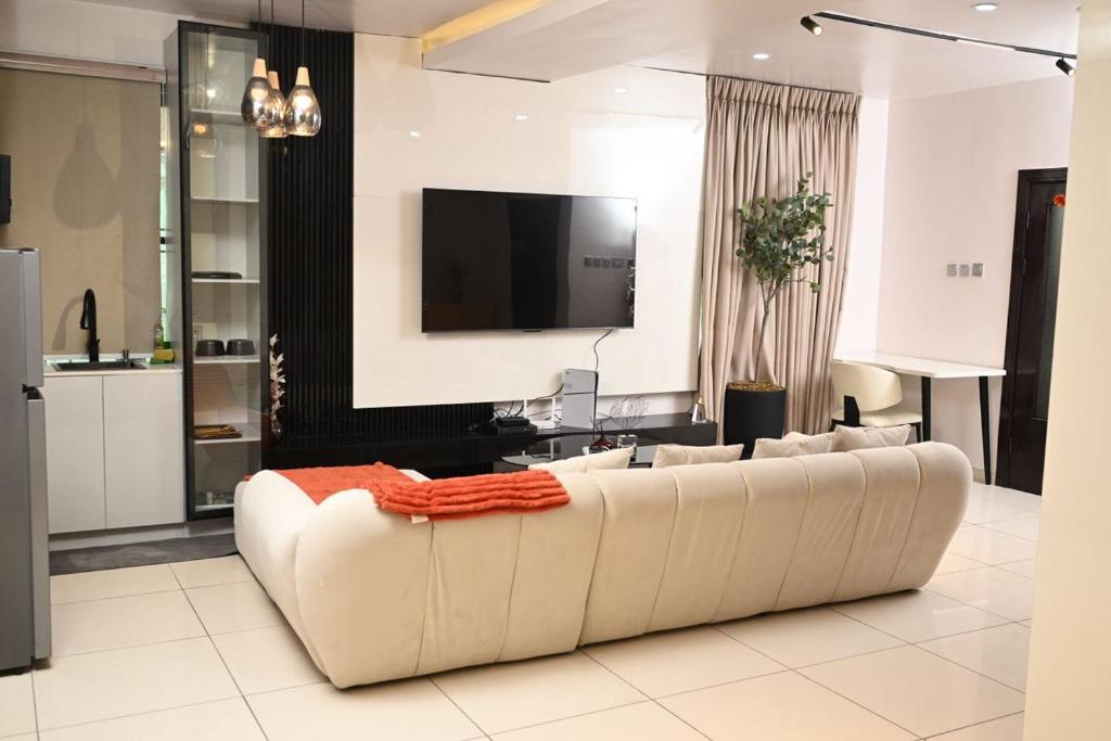 Una sala de estar con un sofá blanco y un televisor. en Goldenstay apartment, en Mama