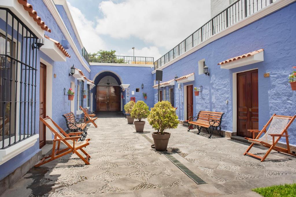 Ein Innenhof mit blauen Gebäuden, Bänken und Bäumen in der Unterkunft Las Torres de Ugarte in Arequipa