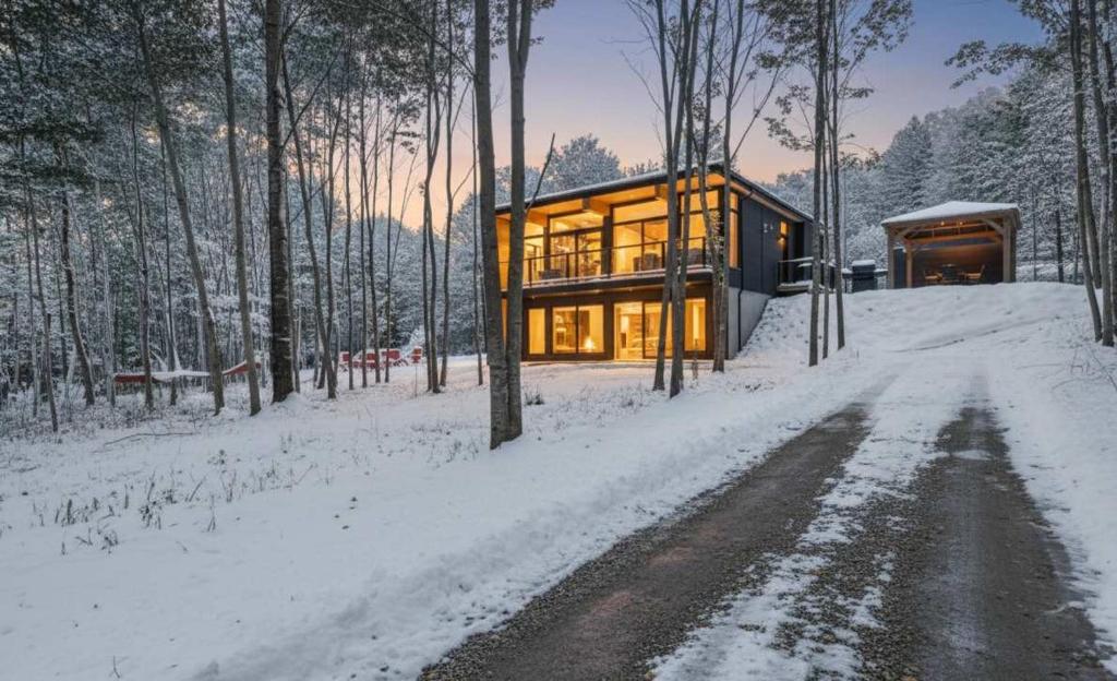 a house in the woods in the snow at Chalet Mid-Century - Lakeside Joseph - Le Charlo in Saint-Pierre-Baptiste