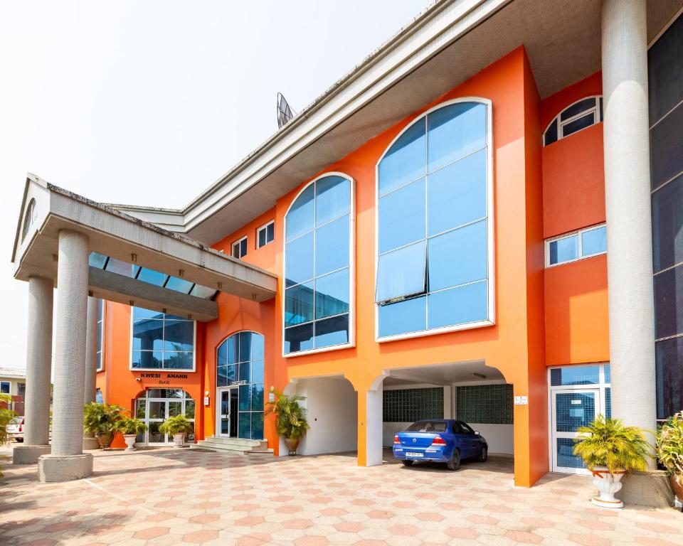 an orange building with a blue car parked outside at Maxlot Hotel in Accra