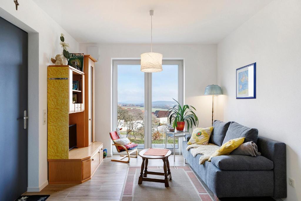 a living room with a couch and a large window at Am Rothen Hang in Oberelsbach