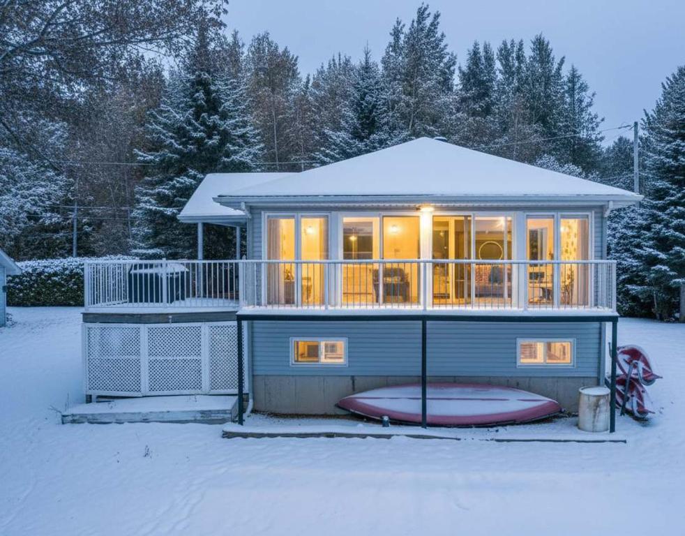 a tiny house in the snow with its lights on at Spa & Lake Access - Le Chic Shack des 3 lacs in Trois-Lacs