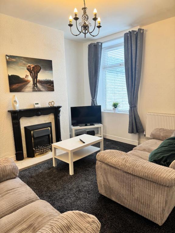 a living room with two couches and a fireplace at Holgate Cottage in Great Harwood