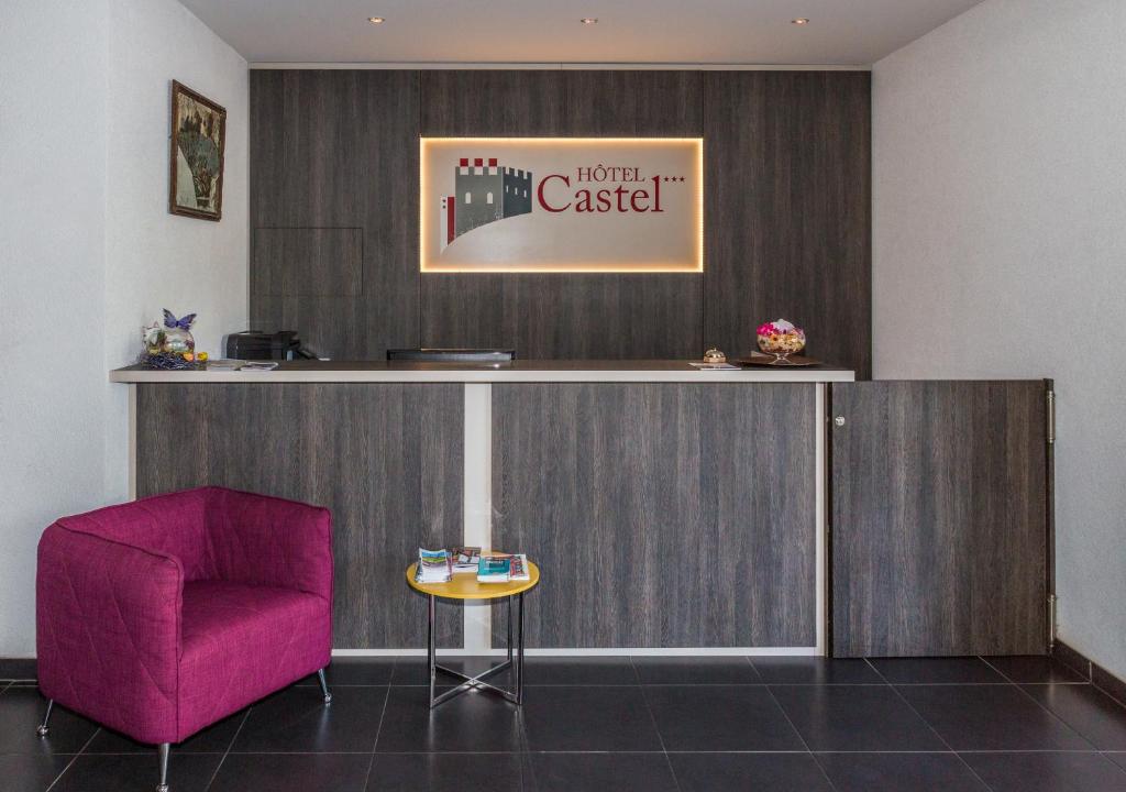 ein Wartezimmer mit einem rosa Stuhl und einer Theke in der Unterkunft Hotel Castel in Sion