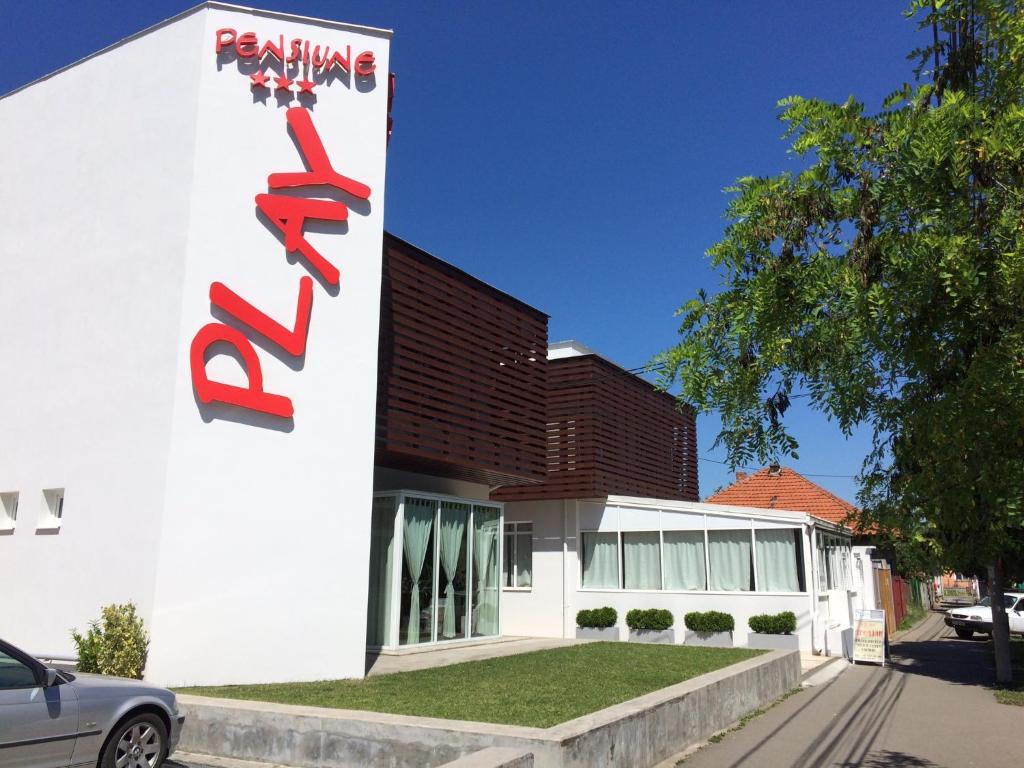 een wit gebouw met een bord aan de zijkant bij Pensiunea Play in Deva