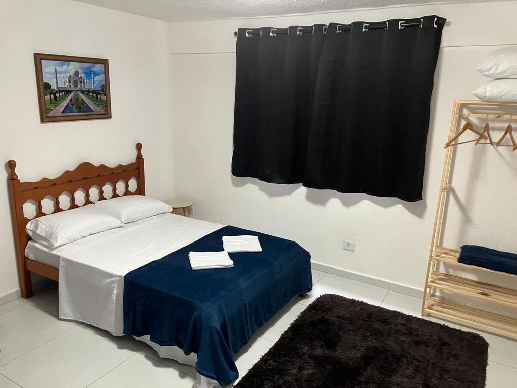 a bedroom with a bed with a blue blanket and a window at Panama 90 - Studio - Região Central in Poços de Caldas