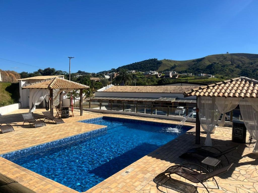 a pool with chairs and umbrellas next to a building at Prime Garden Pousada in Socorro