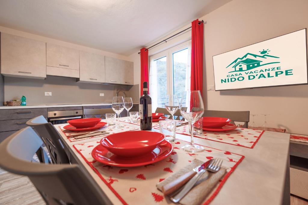 a kitchen with a table with red plates and wine glasses at Casa Adamello in Corteno Golgi