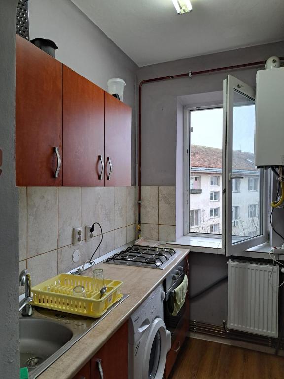 a kitchen with a stove and a sink and a window at Garsoniera in inima Targului de Craciun in Craiova