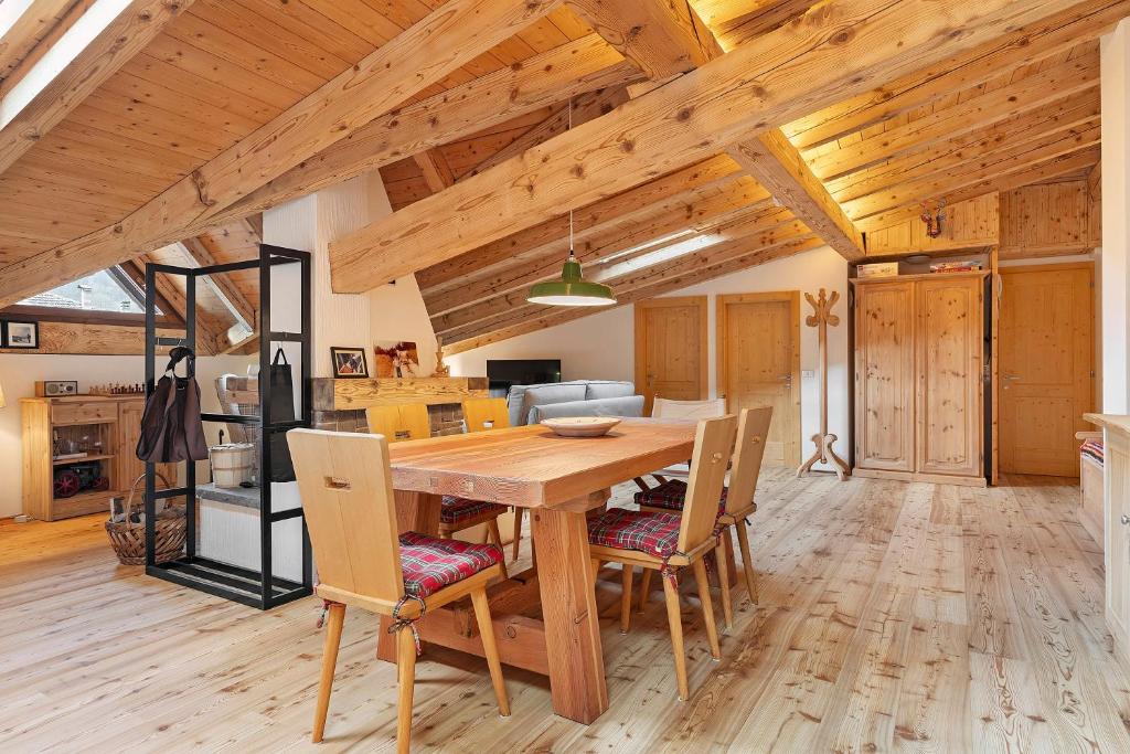 a kitchen and dining room with a wooden table and chairs at Mansarda di charm Valli di Borzago in Mortaso