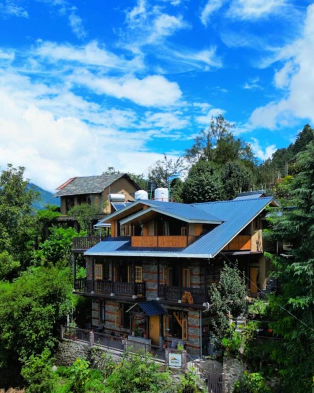 a house on a hill with a blue roof at Rustic Roots Home Stay in Nagar