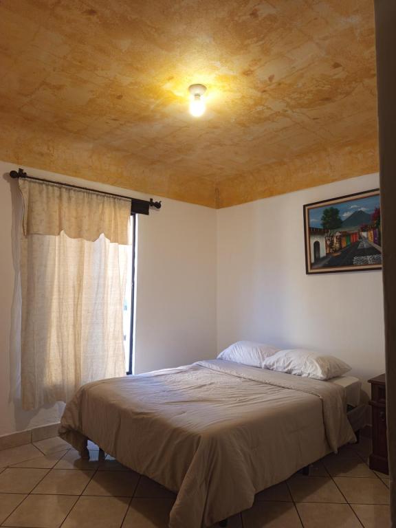 a bedroom with a ceiling with a bed and a window at Antigua Encantó Colonial in Antigua Guatemala