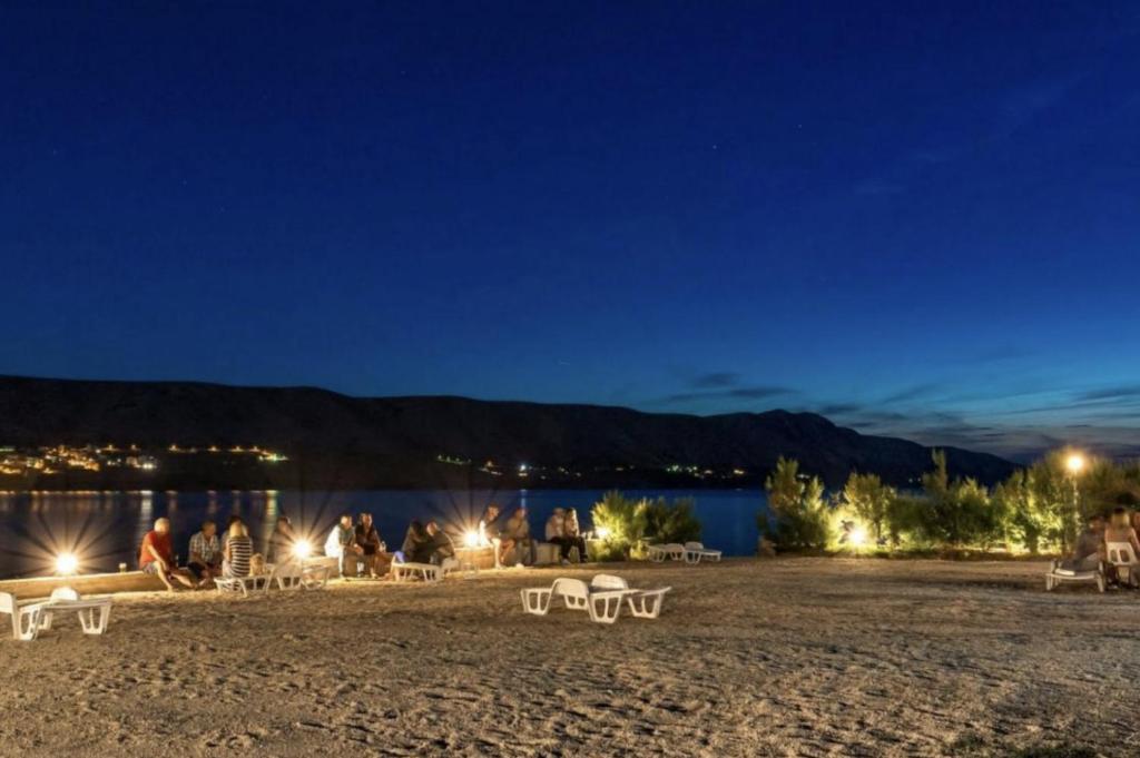 eine Gruppe von Menschen sitzt nachts an einem Strand in der Unterkunft Tonino Apartments & Rooms in Pag