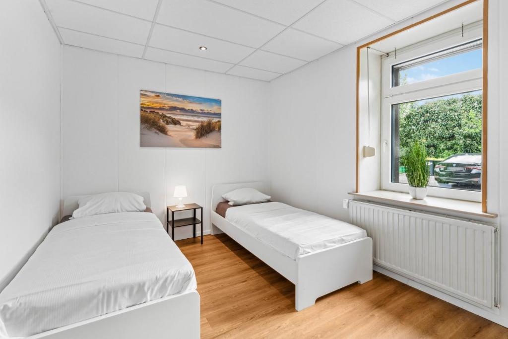 two beds in a white room with a window at For Workers Bedburg Hau in Bedburg Hau