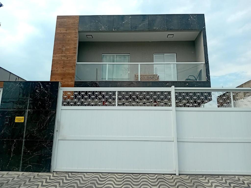 a house with a white fence at Bem praiana in Praia Grande