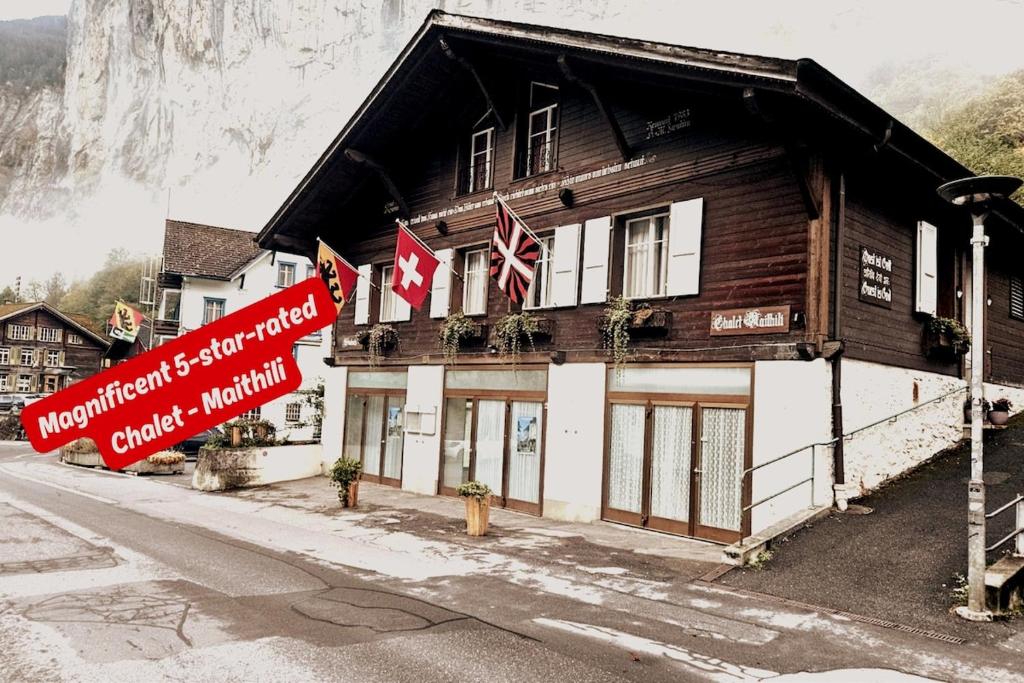 a building with flags in front of a mountain at Chalet Maithili Lauterbrunnen -152-Year-Old Majestic Chalet in Lauterbrunnen