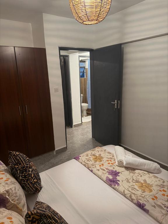 Nzuri Apartment في كيزيمو: غرفة نوم بها سرير ومرآة كبيرة