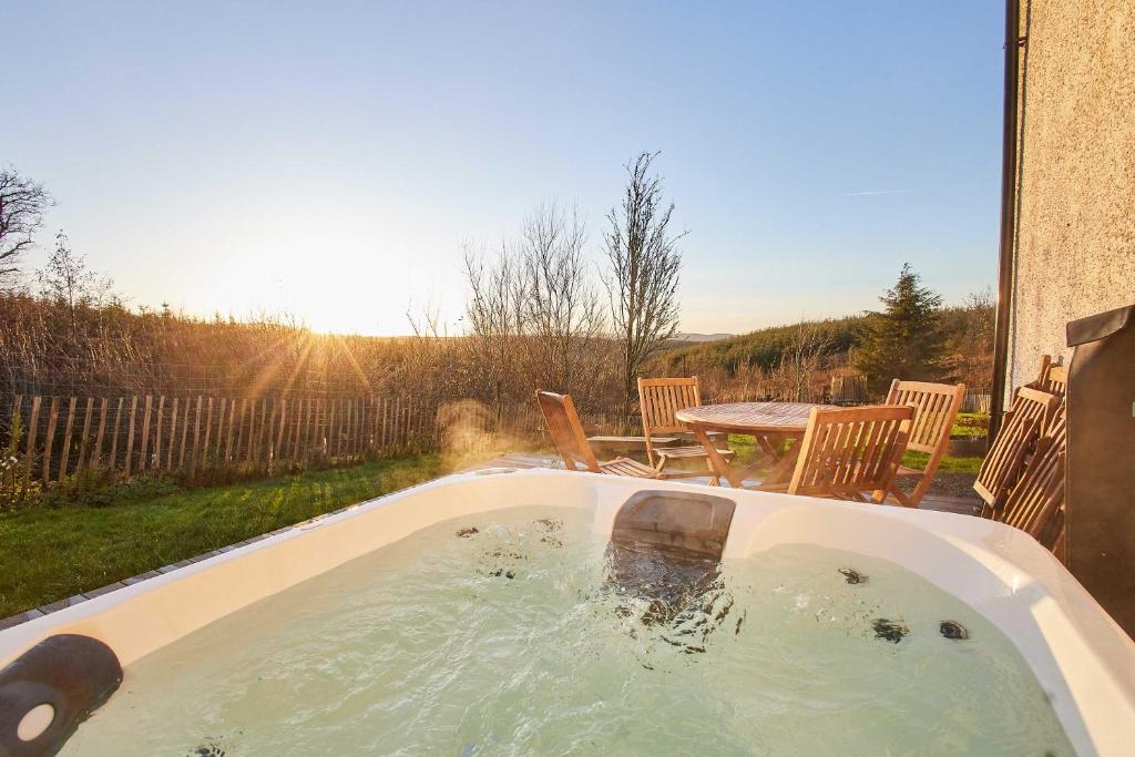 a hot tub with a table and chairs in a backyard at Host & Stay - Carterhouse in Jedburgh