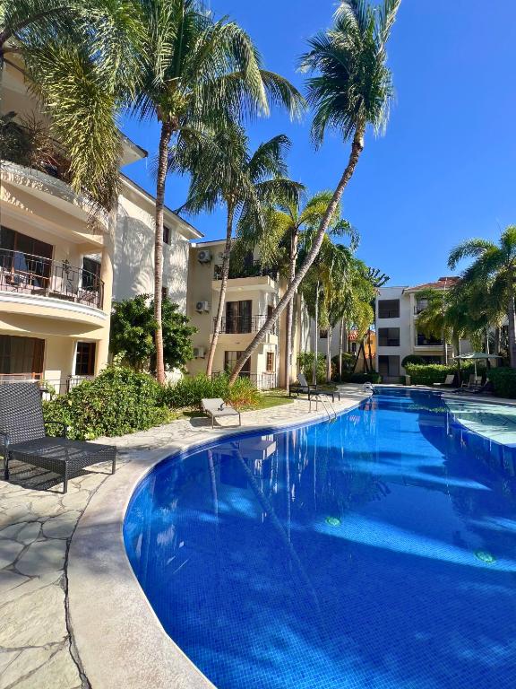 a large swimming pool with palm trees and a building at Apartamento con Piscina 2 Habitaciones Cerca de la Playa Bavaro in Punta Cana