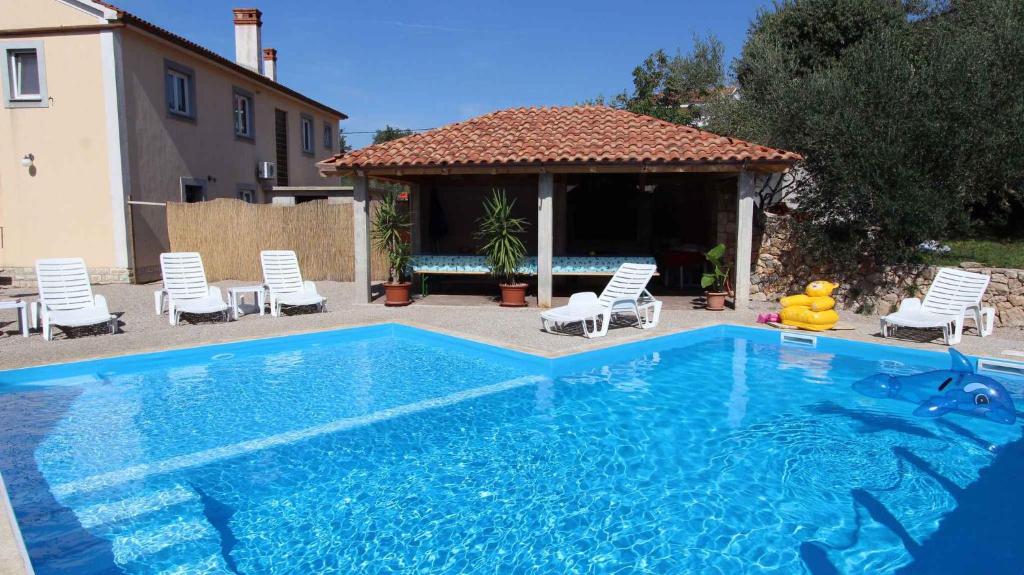 a large swimming pool with chairs and a gazebo at Apartment Malinska, Primorje-Gorski Kotar 20 in Sveti Vid-Miholjice