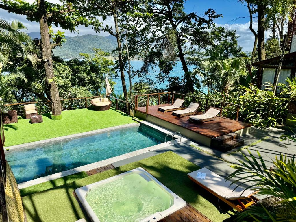 a swimming pool with a deck and chairs and a swimming pool at Casas do Mar in Ilhabela