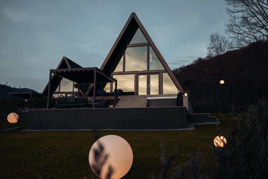 a house with a large window on the grass at Twin Vista A-Frame Cabins in Sovata