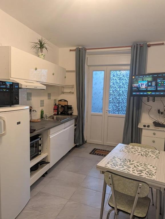 a kitchen with white cabinets and a table and a window at Maison- studio- 2 étoiles in Pluduno