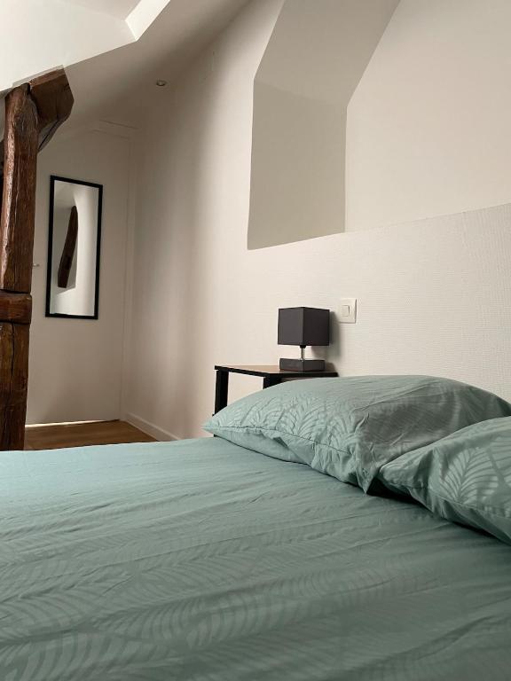 a bedroom with a bed and a table with a lamp at Logement cosy en plein centre de Joigny 2 à 3 pers - Cosy 4 in Joigny