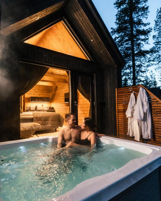 a man and a woman sitting in a bathtub at Silencius Cabin With Private Jacuzzi in Rovaniemi